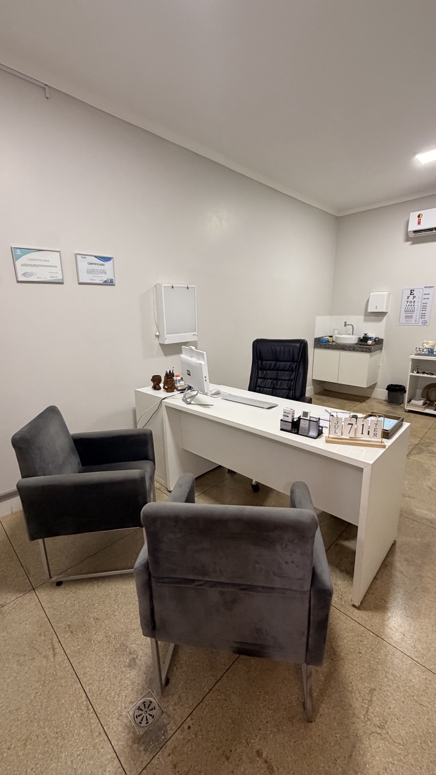 Consultório médico com poltronas e mesa de atendimento
